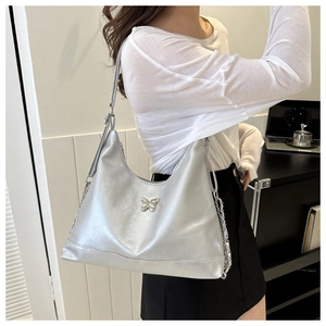 Silver shoulder bag with metallic butterfly buckle and chain strap on female model