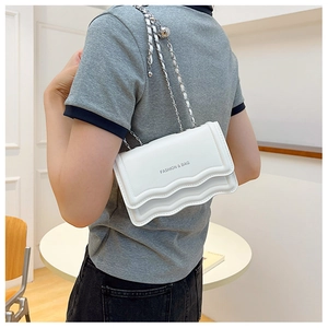 Gros plan d'un sac bandoulière blanc avec bordure ondulée et chaîne en métal