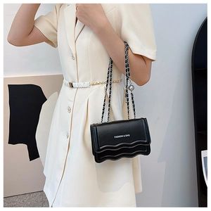 Detail of black chain bag with wavy flap, silver ball charm and metallic lettering