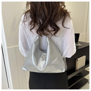 Close-up of silver metallic PU hobo bag with chrome butterfly detail and chain strap