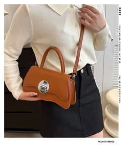 Detailed view of brown crocodile texture bag with unique wave bottom and silver metal clasp