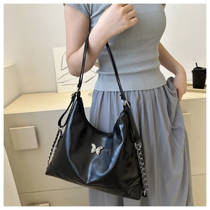 Detail of black PU leather shoulder bag featuring a silver butterfly buckle and chain strap