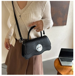 Detail of black crocodile pattern PU leather handbag with silver buckle and wave base