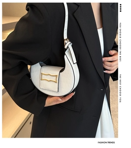 Détail du sac demi-lune blanc avec motif crocodile et boucle dorée sur le mannequin