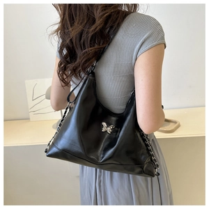 Detailed view of black PU leather hobo bag with silver butterfly buckle and chain strap