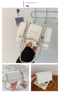 Detail of cream white chain bag with wave-edge flap and decorative silver sphere charm