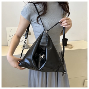 Detail view of black PU leather triangle bag featuring silver butterfly and chain strap