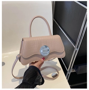 Close-up of beige pink faux crocodile texture handbag with silver round twist lock detail