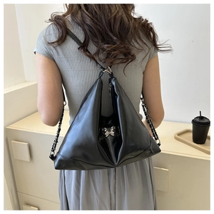 Close-up of black PU leather bag featuring a silver metal butterfly and chain strap