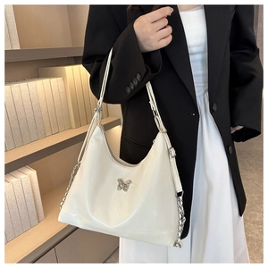 Close-up of creamy white PU leather crescent bag with silver butterfly chain and strap