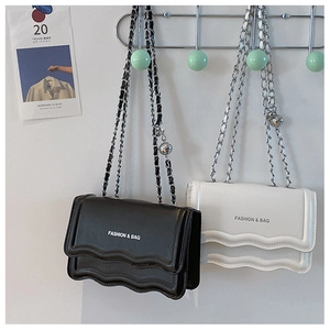 Détail du sac à bandoulière avec rabat ondulé et chaîne en similicuir noir et blanc