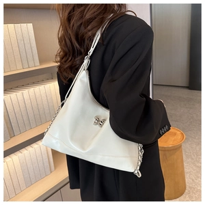 Detail of white PU leather tote bag with silver butterfly charm and chain strap