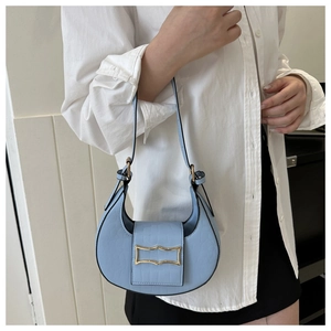 Détail du sac de selle croissant bleu clair avec texture croco et boucle dorée