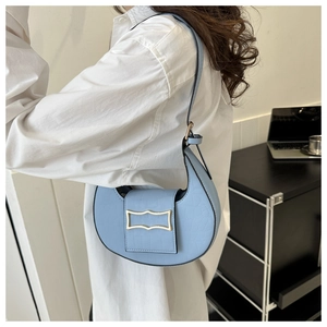 Détail du sac hobo bleu clair avec motif crocodile et boucle dorée sur le mannequin