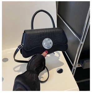 Detail of black crocodile texture handbag with minimalist silver round metal buckle