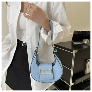 Sac croissant bleu motif crocodile avec boucle dorée porté à l'épaule par un modèle
