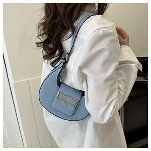 Gros plan d'un sac demi-lune bleu clair à texture crocodile porté par un mannequin