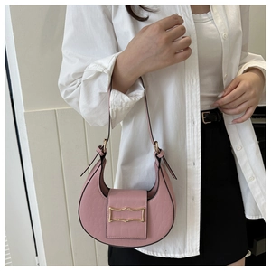 Détail du sac demi-lune rose à motif crocodile et boucle dorée sur chemise blanche