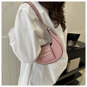 Sac à bandoulière rose demi-lune avec texture crocodile et boucle dorée porté par un mannequin