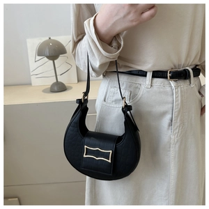 Détail d'un sac baguette noir à effet crocodile avec une boucle métallique dorée