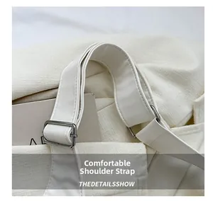 Detail of wide white leather shoulder strap with adjustable silver metal buckle on tote bag