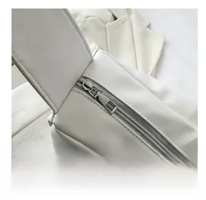 Close-up of matte silver metal zipper head on white leather tote bag with smooth finish