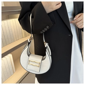 Gros plan sur le motif crocodile blanc et le fermoir en métal doré du sac demi-lune