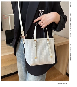 Close-up of white striped bucket bag with gold hardware and woven texture details