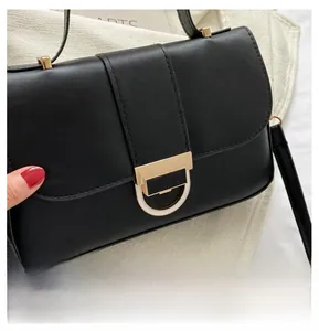 Detailed close-up of the elegant gold D-shaped hardware lock on a black leather handbag