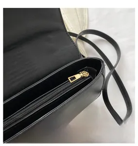 Close-up of the smooth gold zipper and inner pocket detail of the black leather bag
