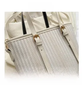 Close-up of white woven bucket bag with gold hardware and adjustable leather strap