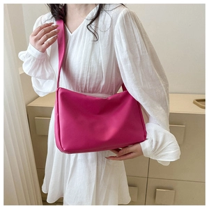 Detail of soft fuchsia crossbody bag worn by a model in a minimalist indoor setting