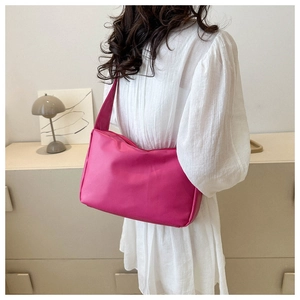 Detailed back view of a magenta minimalist shoulder bag worn with a white dress