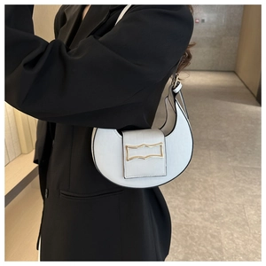 Détail d'un sac demi-lune blanc avec boucle dorée et texture cuir motif crocodile chic