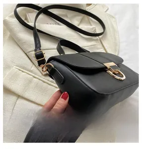 Detail of black leather crossbody bag featuring gold metal buckle and stitching