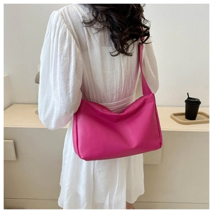 Detail view of a bright pink minimalist soft shoulder bag on a model in modern interior