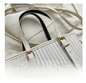 Close-up of vertical weave texture and golden hardware buckle on beige bucket bag