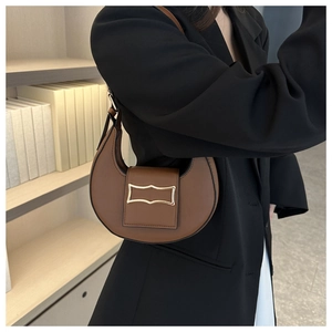 Vue de côté du sac demi-lune marron caramel avec une boucle en métal doré géométrique