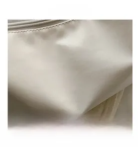 Close-up of fine leather texture and smooth zipper detail on the beige baguette bag