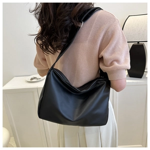 Detailed view of black soft leather shoulder bag with wide strap on a model back