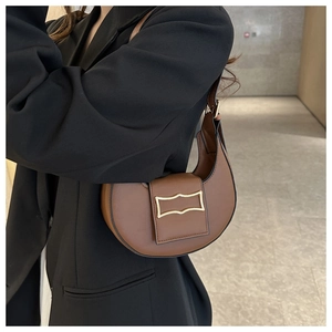 Sac hobo marron à boucle dorée porté avec un blazer noir pour un style chic et sobre