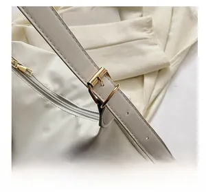 Detail shot of the gold adjustable buckle and shoulder strap on a white crossbody bag
