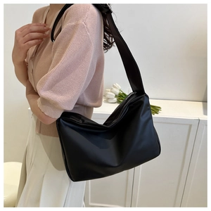 Lifestyle shot of a black minimalist hobo bag with a wide shoulder strap on a model