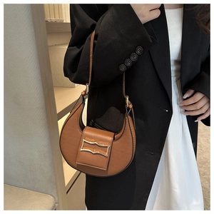 Détails de la texture crocodile et boucle dorée sur le sac bandoulière demi-lune marron