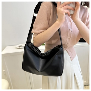 Close-up of a black minimalist soft leather shoulder bag with wide strap and matte texture