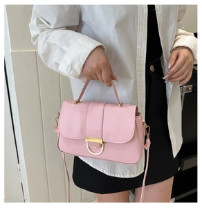 Pink matte crossbody bag with golden clasp shown with a classic white shirt and black skirt
