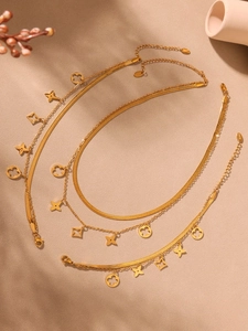 Détail de la chaîne serpent en acier doré avec des breloques trèfle ajourées