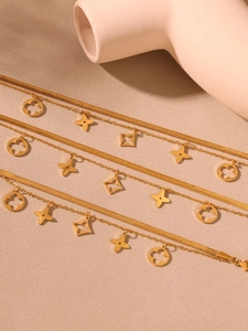 Détail de bracelets dorés multicouches avec chaînes serpent plates et trèfles