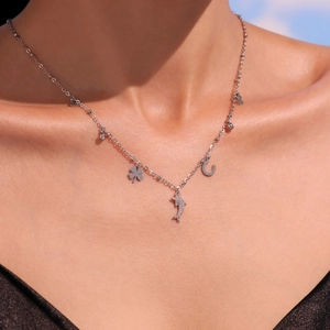 Silver stainless steel dolphin necklace with clover and horseshoe charms worn by a model