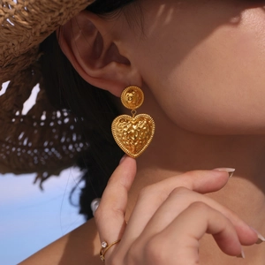 Two-tone heart drop earrings with hammer texture and gold finish on model